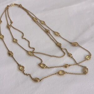 Triple strand gold tone necklace with yellow stones and metal accents